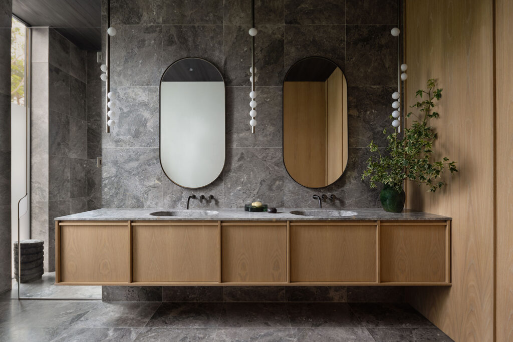 The Bay House — stone primary bath with floating oak vanity