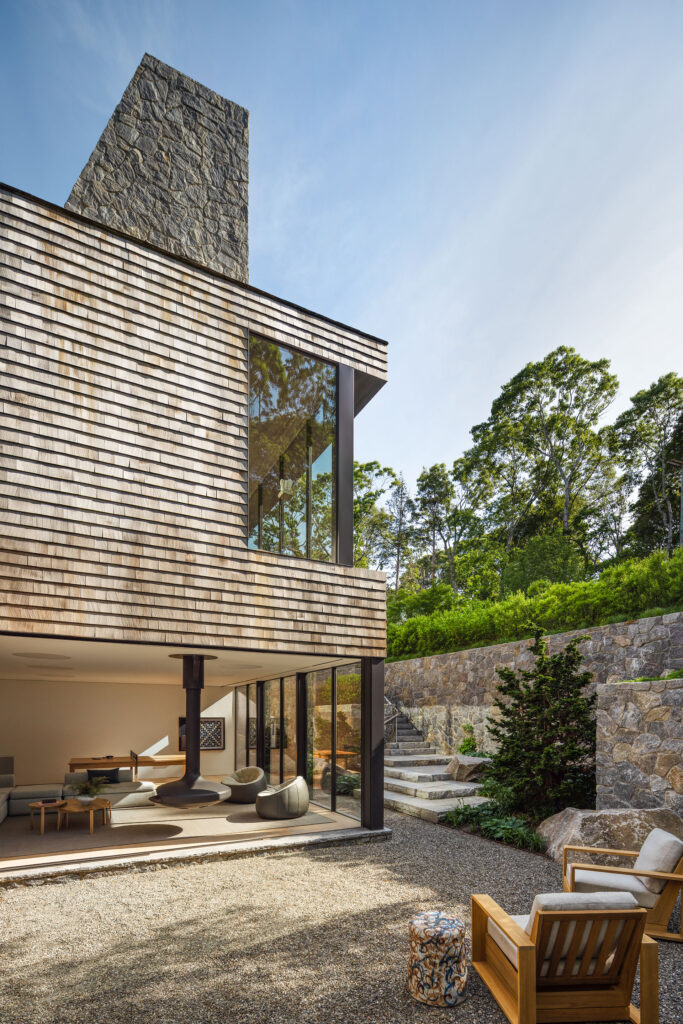 The Bay House — cedar-shingled facade and stone chimney over a gravel courtyard